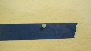 Hammer nail into pre punched hole in tape on to the wall once tape is level